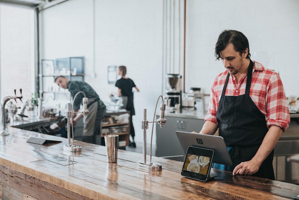 カウンターでタブレットを操作する店舗スタッフ